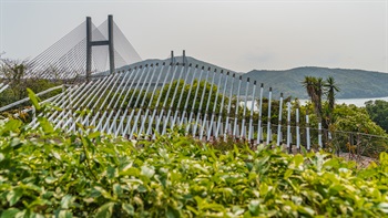 The leaning poles forming the wing point towards the scenic hills and reflect the fan-like pattern of cables of Tsing Ma Bridge.